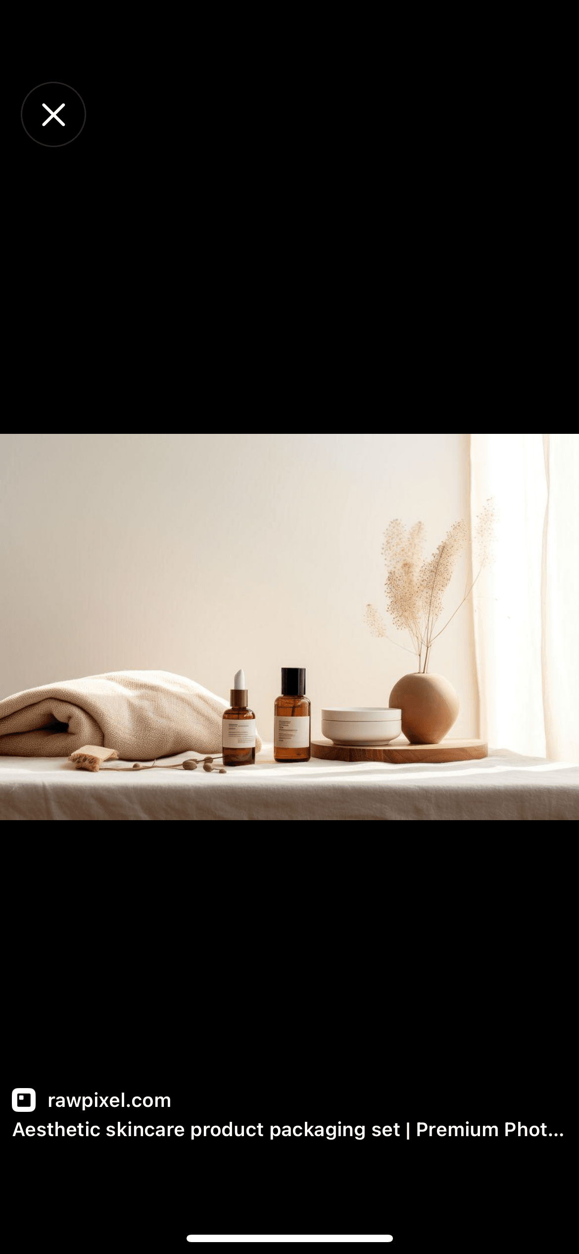 Skincare bottles, cream, folded towels, and dried flowers in soft natural light